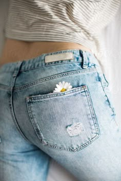 a woman's jeans with a daisy in the back pocket by jodi lenski for stocksy photography