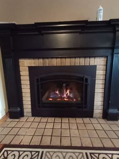 a fireplace with a fire burning in it's mantle next to a rug on the floor