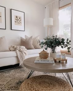 a living room with white couches, coffee table and pictures on the wall above it