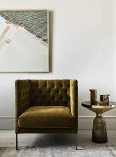 a brown chair sitting next to a table on top of a carpeted floor in front of a white wall