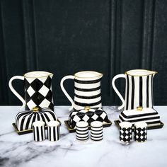 black and white striped vases sitting on top of a marble counter next to each other