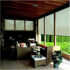 an outdoor living area with chairs, tables and windows covered in blinds that look out onto a green field