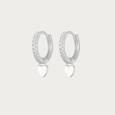 The Silver Gabby Heart Huggies are darling earrings crafted in sterling silver, featuring endearing heart-shaped accents in a classic huggie style. These earrings exude a timeless elegance with a touch of playful charm. Their sleek silver design makes them versatile, ideal for both casual and formal occasions, adding a delightful hint of love and sophistication to any ensemble. Available in various colours Hoop Size: 13mmx13mm Charm Size: 5mmx5mm Silver Plated Tarnish free / Water resistant 💧 Silver Huggie Jewelry With Heart Charm, Elegant Sterling Silver Huggie Earrings With Heart Charm, Silver Heart-shaped Hoop Earrings With Charm, Silver Heart Hoop Earrings With Heart Charm, Silver Sterling Heart Charm Huggie Earrings, Sterling Silver Heart Earrings With White Gold Heart Charm, Silver Sterling Huggie Earrings With Heart Charm, Sterling Silver White Gold Heart Earrings With Heart Charm, Silver Elegant Huggie Earrings With Heart Charm