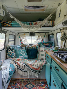 the interior of a camper van with colorful pillows and blankets hanging from the ceiling