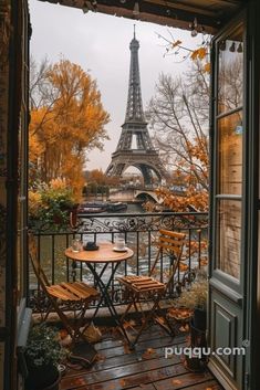 the eiffel tower is seen through an open door to a balcony with tables and chairs