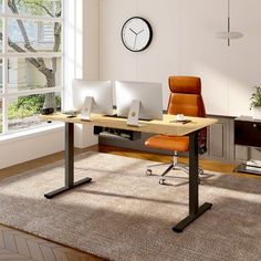 an office area with two computers and a clock mounted to the wall above the desk