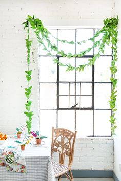 the table is set with flowers and greenery on it, along with two chairs