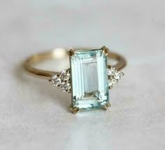 an aquamarinee and diamond ring on a white surface