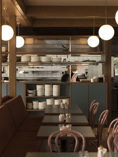 an empty restaurant with tables and chairs in front of the counter, along with lights hanging from the ceiling