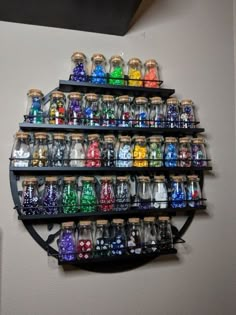 a wall mounted shelf filled with lots of different colored glass bottles on top of it