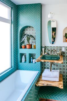 a bathroom with green tiles and blue walls, along with a white bathtub in the corner