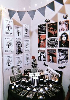 a black and white halloween table setting with candles, decorations and pictures on the wall