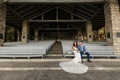 a bride and groom sitting on benches in front of an empty stadium bleachers