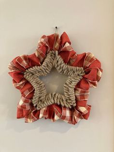 a red and white checkered star shaped wreath hanging on the side of a wall