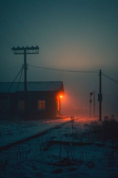 a train station in the middle of winter at night with fog and light coming from its windows