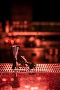 two silver cups sitting on top of a red counter next to each other in front of a bar