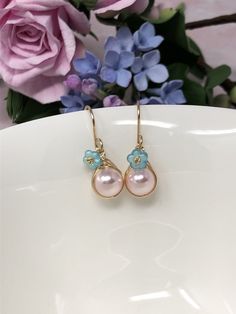 These one of a kind flowering beauties feature soft, blush pink Swarovski Crystal pearls that are meticulously wrapped in 14kt yellow gold filled wire. The braided detailing looks amazing with these pearls. Accented with gold-dusted, aqua Czech glass flowers and gracefully suspended from handcrafted French ear wires. These are perfect for Spring, Summer and for bridesmaids gifts! - All components are 14kt yellow gold filled. - Swarovski Crystal pearls, Czech Glass flower beads. - Pearl dangles a Feminine Flower Earrings With Ear Wire For Gifts, Handmade Feminine Flower Earrings For Spring, Pink Handmade Flower Earrings For Spring, Handmade Feminine Dangle Flower Earrings, Pink Earrings With Handmade Flowers For Spring, Feminine Jewelry With Matching Earrings For Spring, Elegant Pink Flower Earrings For Spring, Handmade Feminine Drop Flower Earrings, Handmade Floral Drop Earrings For Spring