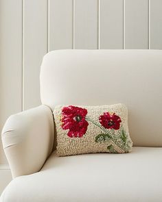 a white chair with a red flower pillow on it