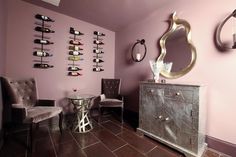 a room with two chairs, a table and a wine rack on the wall above it