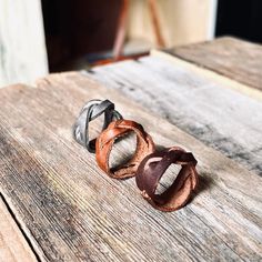 three different colored rings sitting on top of a wooden table next to another ring that has been made out of leather