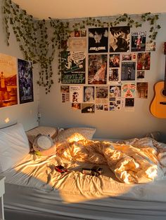 an unmade bed in a bedroom with posters on the wall and plants growing over it