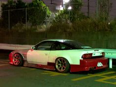 a white and red car parked in a parking lot next to a street light at night