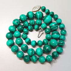 On offer is this high quality Vintage natural emerald green Malachite graduated bead necklace. This beautiful vintage necklace consists of genuine rich emerald blue green round beads that is hand-knotted with silk cord and finished with a sterling silver gold filigree clasp with a safety latch that opens and closes tightly. These Malachite gems are highly polished and very lustrous. The glossy Malachite beads range in size from 1/2 inch diameter at the front to 6/16 inch diameter at the clasp. T Single Strand Round Beaded Emerald Necklaces, Emerald Single Strand Necklaces With Round Beads, Emerald Single Strand Necklace With Round Beads, Single Strand Necklace With Round Emerald Beads, Turquoise Round Beads Emerald Necklace, Classic Green Gemstone Beads Necklace, Emerald Beaded Necklaces With Natural Stones, Polished Emerald Beaded Necklaces, Elegant Green Oval Bead Necklaces