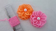 three crocheted flowers sitting on top of a ruler