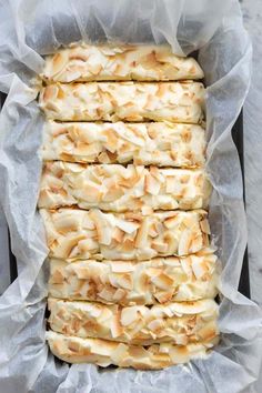 a loaf of bread with white frosting on top in a baking pan covered in wax paper