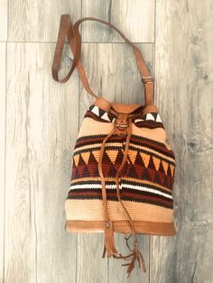 a brown and tan bag sitting on top of a wooden floor next to a wall