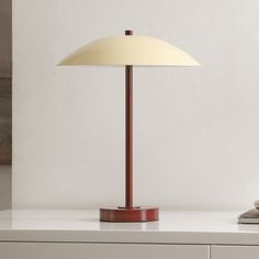 a lamp sitting on top of a white table next to a book and some books