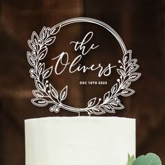 a white wedding cake with the words mr and mrs on it, surrounded by greenery