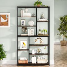 a book shelf with books, plants and pictures on it in the corner of a room