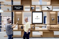 two men standing in front of a display with cell phones