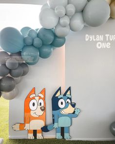 two cartoon characters are standing next to each other in front of balloons and streamers