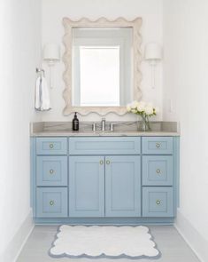 a bathroom with blue cabinets and a white rug