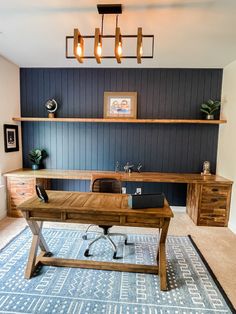 a wooden desk sitting in the middle of a living room next to a blue rug