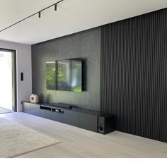 a modern living room with black and white walls, an entertainment center and large sliding glass doors