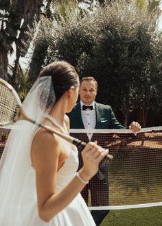 a man in a tuxedo standing next to a woman holding a tennis racquet