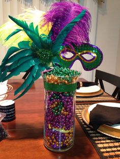 a table topped with a vase filled with beads and a purple mask on top of it