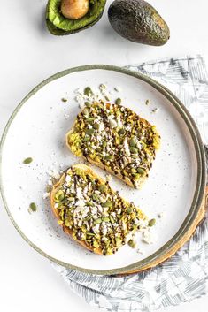 two pieces of toast on a plate with avocado and sprinkles