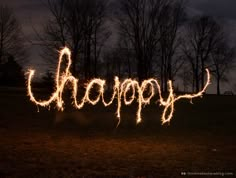 the word happy written with sparklers in front of trees