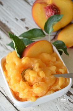 a small white bowl filled with macaroni and cheese next to two peaches