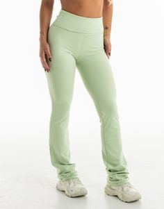 a woman in green pants is posing for the camera with her hands on her hips