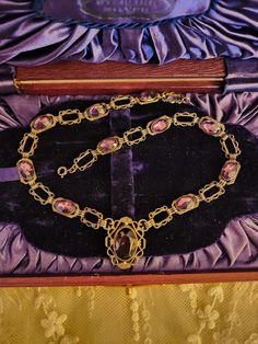 This listing is for an antique sterling silver and purple Amethyst paste stones necklace. The necklace is 15" long and the little central pendant drop is 1" long x 3/4" wide. There are 11 total Amethyst paste stones, with the cental stone being the largest. There is a flea bite on the central stone above the top facets but is very hard to see without magnification. This is a preloved, antique necklace and will show signs of wear. There may be scratches ,flea bites as mentioned above and abrasions to this piece.My items are sold as found and I do my best to describe ,what you will be receiving when you make a purchase. Wear is commensurate with age. This piece tests as silver. The 10 side stones are closed back and may have foiling to them but I cannot see the backs so it is my best guess t Vintage Oval Jeweled Necklaces, Vintage Oval Jeweled Necklace, Vintage Jeweled Oval Necklace, Antique Jeweled Collectible Necklace, Purple Jeweled Necklace For Formal Occasions, Formal Purple Jeweled Necklace, Antique Silver Jeweled Necklace, Antique Jeweled Silver Necklace, Antique Silver Jeweled Necklaces