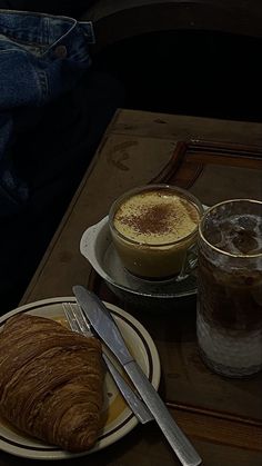 there is a croissant and coffee on the table next to eachother