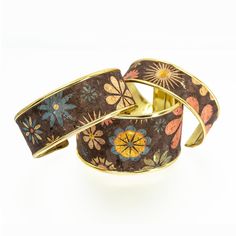 two bracelets with flowers on them sitting next to each other in front of a white background