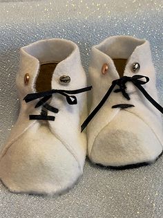 a pair of white baby shoes with black laces