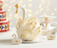 a white swan is sitting on a plate next to three small swans and two cakes