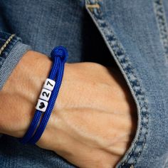 a person wearing a blue bracelet with white letters on it